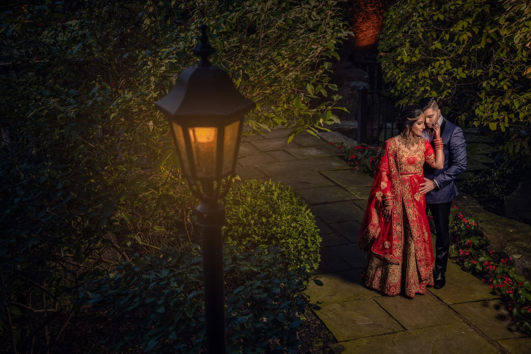 A wedding couple beside a glowing garden lantern